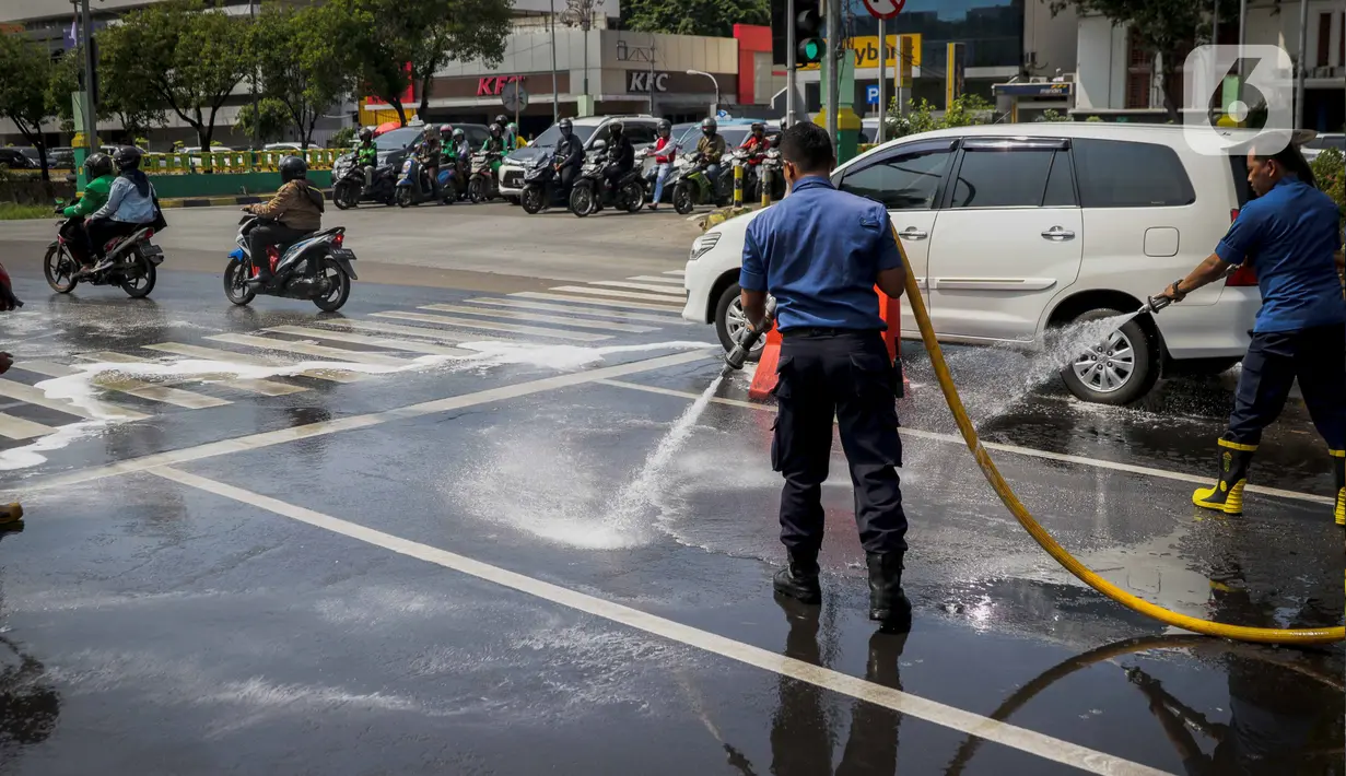 Sejumlah personil pemadam kebakaran membersihkan tumpah oli yang terjadi di Jalan Veteran depan Gedung Krida Bakti, Jakarta, Kamis (16/1/2020). Petugas damkar  melakukan pembersihan dengan cairan deterjen maupun campuran khusus agar jalan tersebut tidak lagi licin. (Liputan6.com/Faizal Fanani)