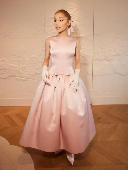Ariana Grande menghadiri Upacara Pembukaan pada 26 Juli dengan gaun sutra berpinggang rendah warna merah muda Glinda karya Thom Browne. [@arianagrande].
