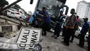 Petugas mengevakuasi bus gandeng TransJakarta yang menabrak pagar pembatas jalan, di Jalan Gunung Sahari, Jakarta, Selasa (6/9). Tak ada korban jiwa dalam insiden yang diduga lantaran sopir mengantuk tersebut. (Liputan6.com/Faizal Fanani)