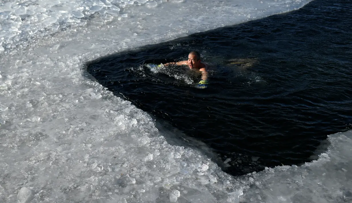 Seorang perenang es berenang di danau beku pada hari musim dingin di Beijing  (6/1/2021). Berenang di musim dingin adalah kegiatan olahraga yang jarang dijumpai kecuali di beberapa negara dengan musim dingin yang cukup panjang. (AFP/Wang Zhao)