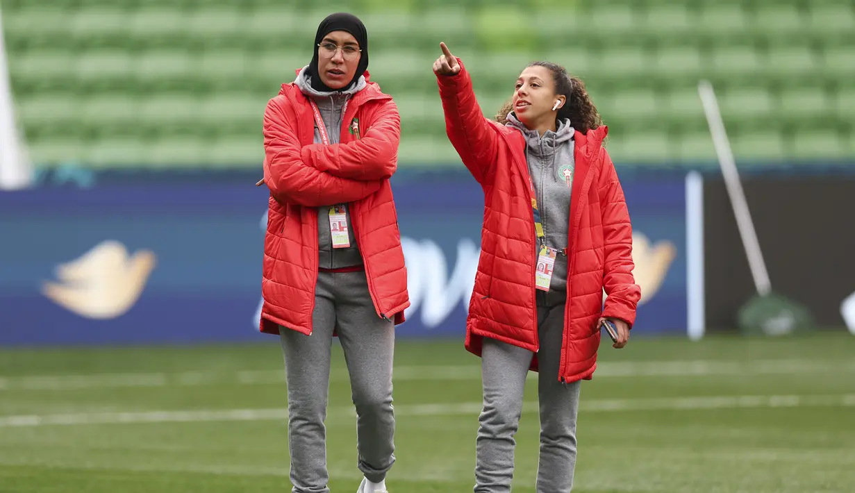 Pesepak bola wanita Timnas Maroko, Nouhaila Benzina (kiri) dan rekannya Fatima Gharbi berjalan menyusuri lapangan dalam sesi latihan di Melbourne Rectangular Stadium, Melbourne (23/7/2023) jelang menghadapi Jerman pada laga pertama Grup H Piala Dunia Wanita 2023. (AP Photo/Victoria Adkins)