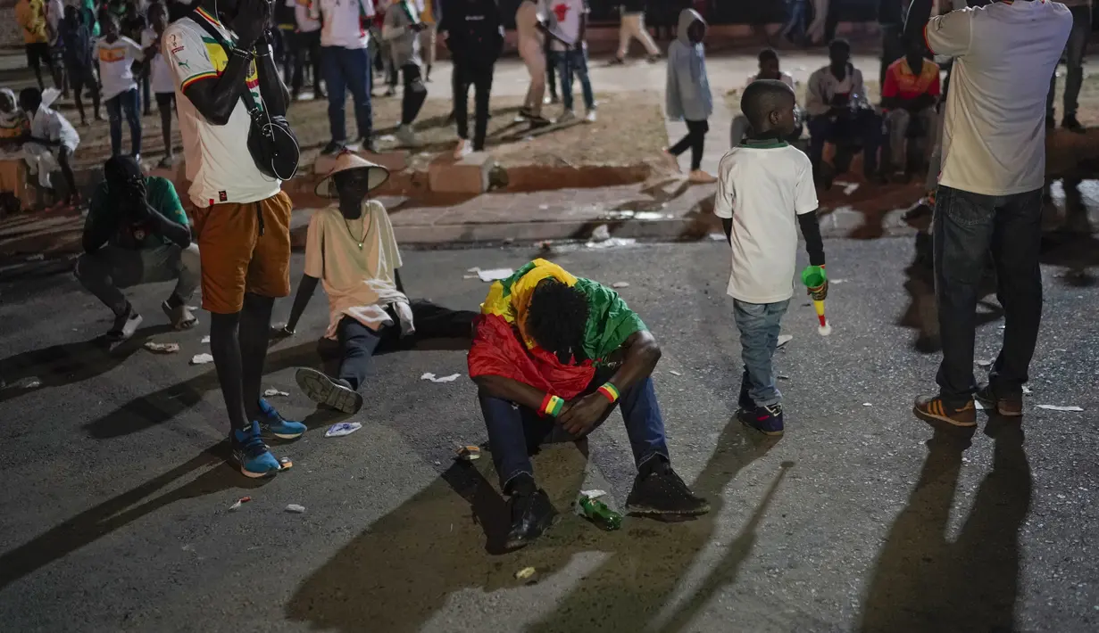 Suporter Senegal bereaksi setelah menyaksikan laga babak 16 besar Piala Dunia 2022 saat tim kesayangan mereka melawan Inggris di Qatar, lewat layar video yang dipsang di fan zone di Dakar, Senin (5/12/2022) dini hari WIB. Senegal ditaklukkan Inggris dengan skor 0-3. (AP Photo/Leo Correa)