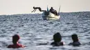 Seorang anak melompat dari sebuah kapal di Pantai Jazera di pinggiran Mogadishu, Somalia (24/11). Pantai ini jadi tempat rekreasi populer bagi warga Somalia. (AFP Photo/Mohamed Abdiwahab)