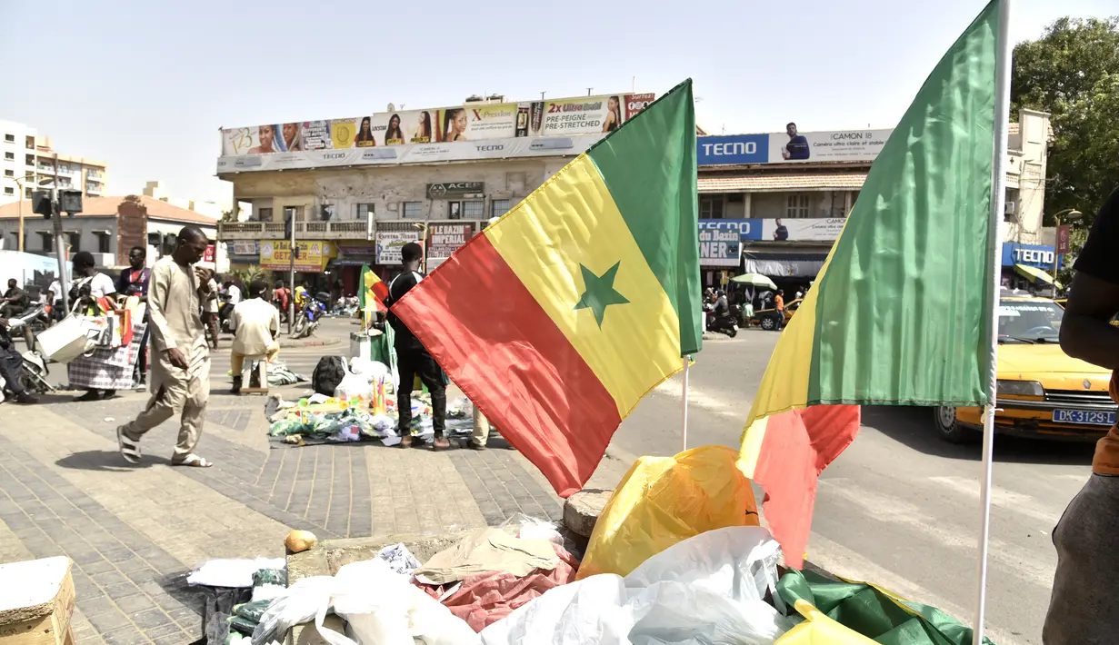 Bendera Senegal dipajang untuk dijual di jalan-jalan Dakar (4/2/2022). Senegal akan bertanding melawan Mesir pada babak final Piala Afrika 2021 di Paul Biya stadium, Senin (7/2/2022) dini hari WIB besok. (AFP/Seyllou)