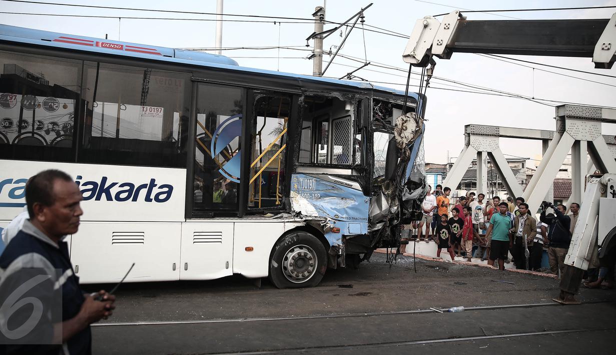 Alat berat mengevakuasi bus transjakarta yang mengalami kecelakaan dengan kereta api di perlintasan Jalan Mangga Dua, Jakarta, Kamis (19/5). Kecelakaan itu melibatkan bus Transjakarta, mobil Avanza dan kereta Senja Utama Solo. (Liputan6.com/Faizal Fanani)