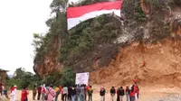 Bendera merah putih raksasa berkibar di Tebing Palai, Desa Garagata, Kecamatan Jaro, Kabupaten Tabalong, Kalsel, pada perayaan HUT ke-79 Kemerdekaan RI, Sabtu (17/8/2024). (Liputan6.com/ Dok FPTI Tabalong)