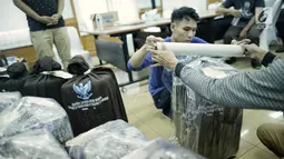 Petugas membungkus plastik paket berisi surat suara Pemilu 2019 susulan di Gedung KPU RI, Jakarta, Minggu (28/4/2019). Surat suara susulan tersebut akan dikirimkan ke Kuala Lumpur, Malaysia untuk pelaksanaan pemilihan Presiden dan Wakil Presiden. (Liputan6.com/Faizal Fanani)