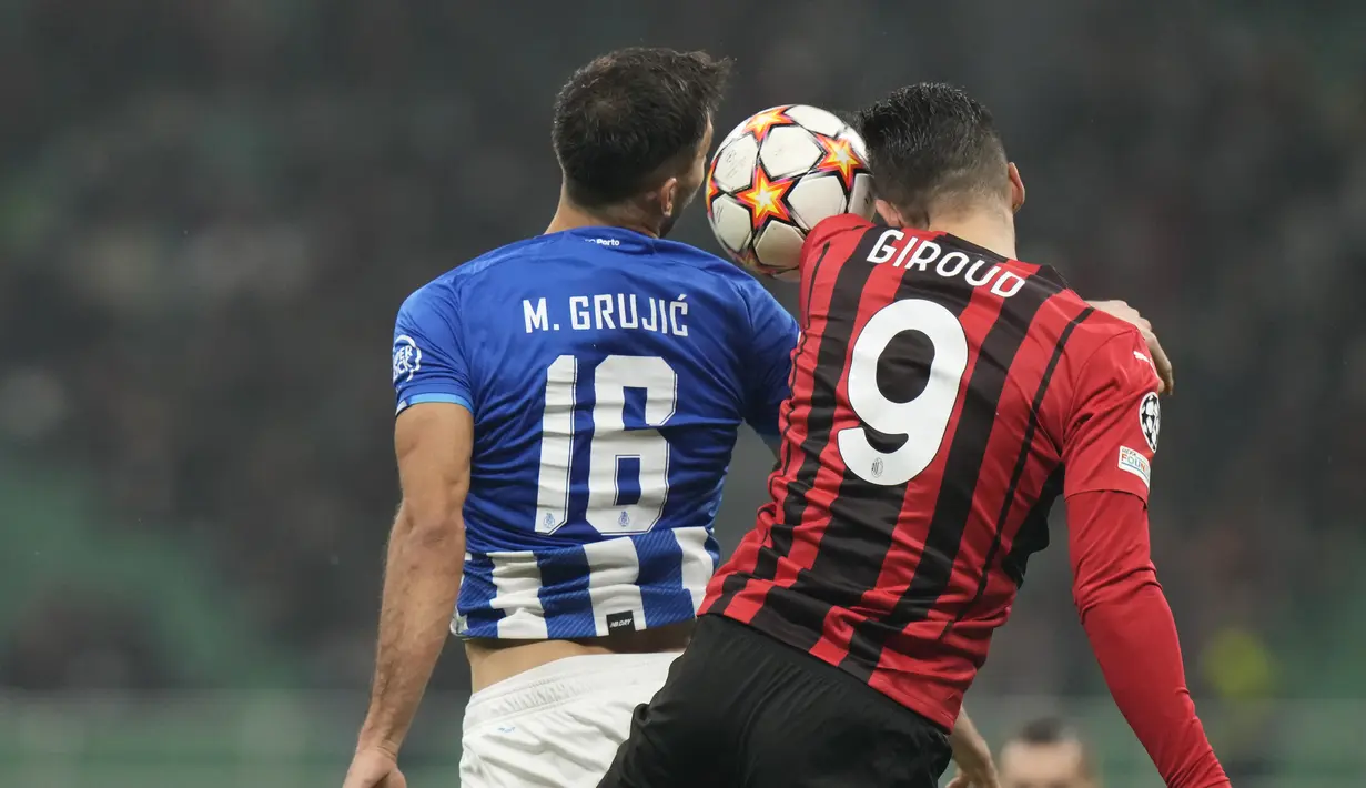 Gelandang FC Porto, Marko Grujic melompat untuk berebut bola dengan penyerang AC Milan Olivier Giroud pada matchday kelima Grup B Liga Champions di San Siro, Kamis (4/11/2021) dini hari WIB. AC Milan makin terpuruk setelah hanya mampu bermain imbang dengan Porto 1-1. (AP Photo/Luca Bruno)