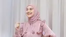 Irish Bella tampil dengan dress shimmer warna pink dengan aksen pita di bagian depan. Dipadukan kerudung segi empat model lilit di leher warna pink serasi. [@_irishbella_]