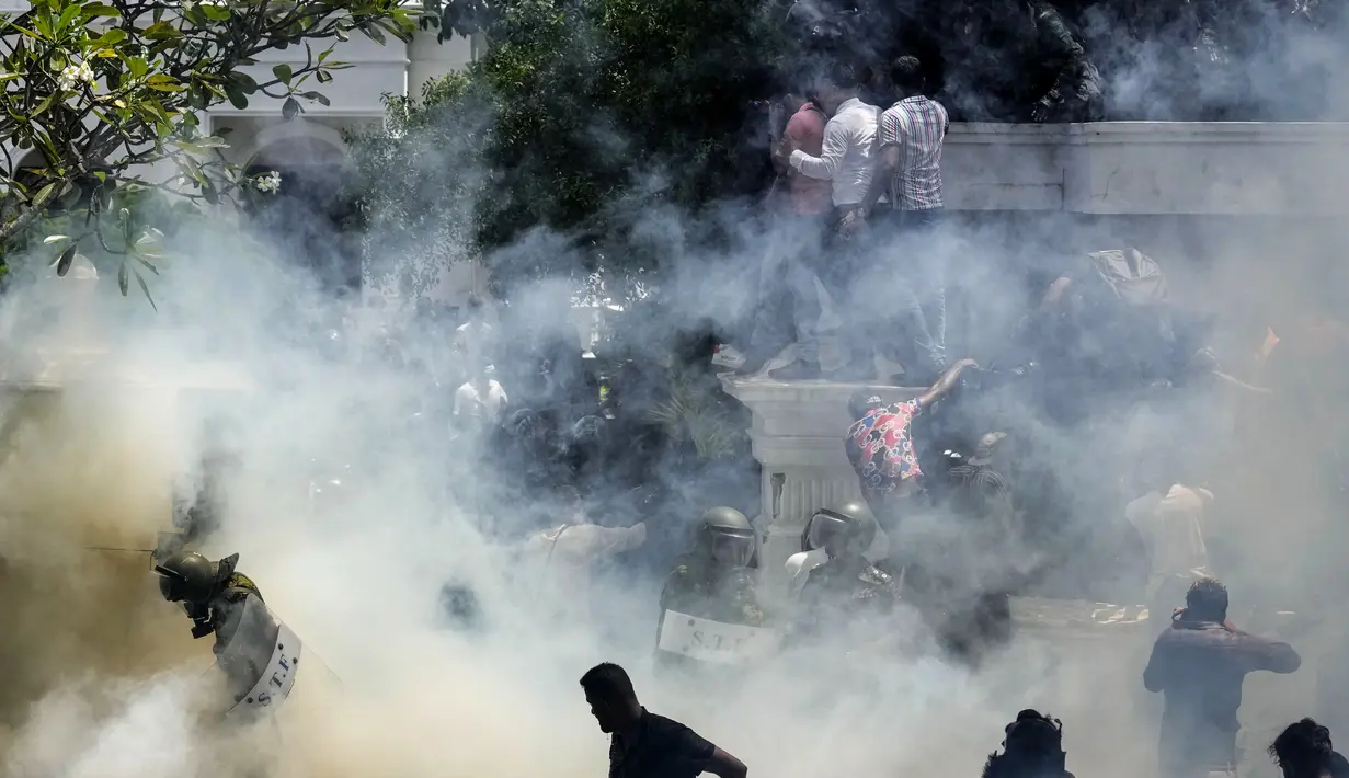 Tentara Sri Lanka terjebak dalam asap dengan pengunjuk rasa menyerbu kompleks kantor perdana menteri Ranil Wickremesinghe di Kolombo, Sri Lanka, Rabu (13/7/2022). Presiden Sri Lanka melarikan diri dari negara itu, beberapa jam sebelum dia berjanji untuk mengundurkan diri di bawah tekanan dari pengunjuk rasa yang marah. (AP Photo/Rafiq Maqbool)