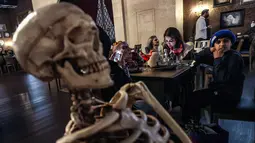 Tengkorak duduk di meja seberang pengunjung di restoran "Shadows" bertema horor di kota hiburan Boulevard, Riyadh, Arab Saudi, 19 Januari 2022. Restoran tersebut menawarkan pengalaman unik kepada pelanggan dari hidangan dengan tengkorak dan darah ditemani zombie serta vampir. (Fayez Nureldine/AFP)
