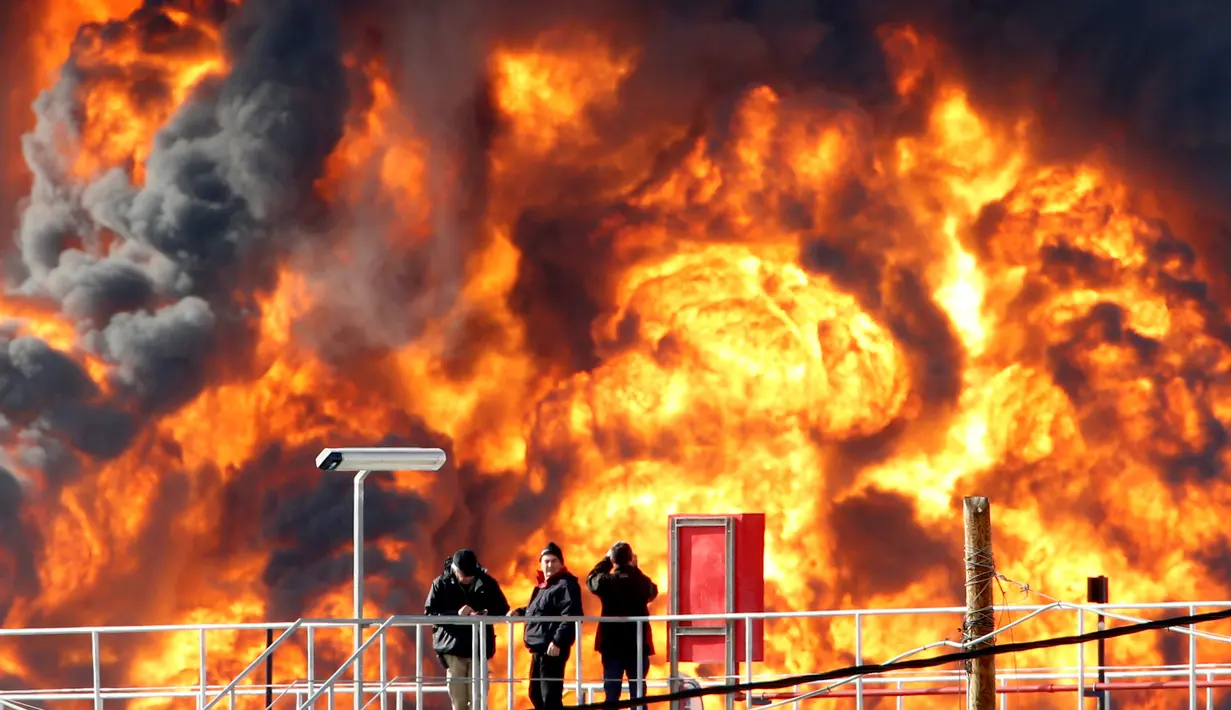 Pekerja mengamati kebakaran besar yang melanda salah satu tangki kilang minyak di Haifa, utara kota Israel, Minggu (25/12). Tidak ada korban jiwa dalam insiden yang masih belum diketahui penyebab kebakaran tersebut. (REUTERS/Baz Ratner)