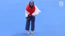 Atlet Taekwondo putri Indonesia, Defia Rosmaniar berselimut bendera Merah Putih saat merayakan kemenangan atas Salahshouri Marjan (Iran) pada Final Women Individual Poomsae di JCC, Jakarta, Minggu (19/8). (Liputan6.com/Helmi Fithriansyah)