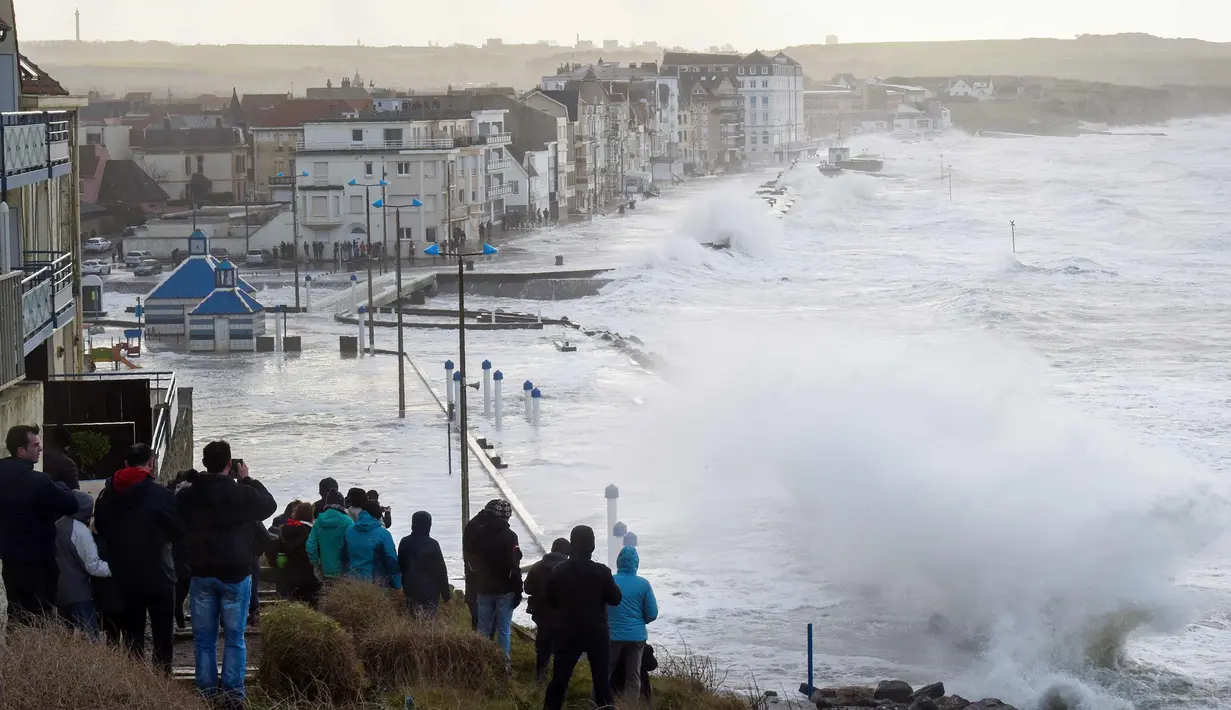 Sejumlah warga berkumpul menyaksikan debur ombak yang disebabkan badai Eleanor di pinggir laut Wimereux, utara Prancis (3/1). Badai Eleanor memaksa penghentian layanan transportasi dan kereta api.  (AFP Photo/Francois Lopresti)