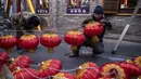Para pekerja memasang lentera tradisional Tiongkok di sepanjang gang menjelang Tahun Baru Imlek di Beijing, China, 2 Februari 2021. Imlek tahun ini jatuh pada tanggal 12 Februari 2021. (NOEL CELIS/AFP)