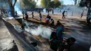 Para demonstran antipemerintah berkumpul di antara gas air mata yang ditembakkan polisi untuk membubarkan protes di Santiago, Chile, Jumat (27/12/2019). Protes Chile berubah menjadi gerakan yang jauh lebih besar dan luas dengan daftar panjang tuntutan. (AP Photo/Fernando Llano)