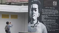 Seorang pengunjung mengabadikan mural penulis Chairil Anwar Taman Ismail Marzuki, Jakarta, Selasa (13/11). Mural tersebut dibuat dalam rangka memeriahkan Hari Pahlawan. (Liputan6.com/Immanuel Antonius)