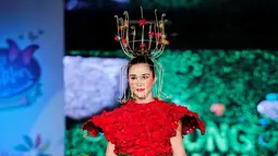 Seorang model berjalan diatas catwalk mengenakan busana yang terbuat dari aneka daun dan bunga yang dominan berwarna merah saat pergelaran Biofashion di Cali, Kolombia (19/11). (Reuters/Jaime Saldarriaga)