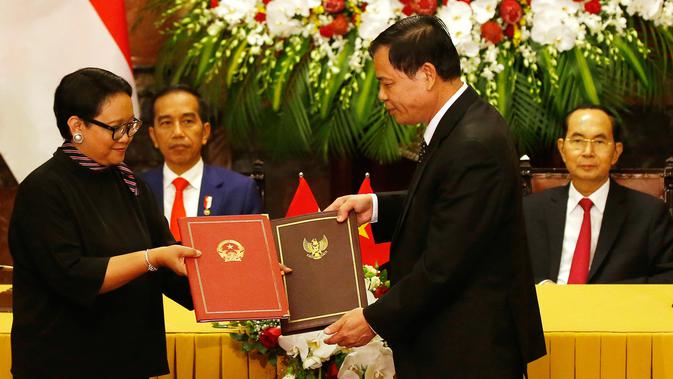 Presiden Joko Widodo menyaksikan Menteri Luar Negeri Retno Marsudi bertukar dokumen dengan Menteri Pertanian Vietnam Nguyen Xuan Cuong setelah upacara penyambutan di Istana Kepresidenan, Hanoi, Vietnam (11/9). (AP Photo/Bullit Marquez)