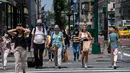 Orang-orang berjalan menyusuri 5th Avenue pada hari yang hangat di New York City (7/6/2021). Cuaca yang hangat di New York dimanfaatkan warga untuk membaca buku hingga berjalan-jalan. (AFP/Angela Weiss)