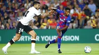 Penyerang Barcelona, Ansu Fati, berusaha melewati bek Valencia, Ezequiel Garay, pada laga La Liga di Stadion Camp Nou, Sabtu (14/9). Barcelona menang 5-2 atas Valencia. (AP/Joan Monfort)