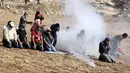 Pengunjuk rasa Palestina melaksanakan salat di tengah tembakan gas air mata tentara Israel di dekat desa Beit Dajan, Palestina (9/10/2020). Insiden terjadi ketika pengunjuk rasa menggelar aksi memprotes pencaplokan tanah yang dilakukan Israel untuk perluasan permukiman Yahudi. (AFP/Jaafar Ashtiyeh)