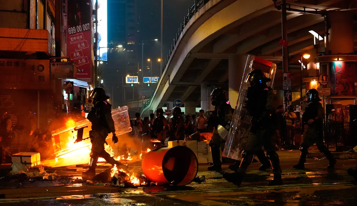 Polisi antihuru-hara tiba setelah demonstran membakar sampah di Hong Kong, Minggu (29/9/2019). Demonstrasi pada akhir pekan ini sendiri digelar beberapa hari menjelang perayaan kemerdekaan China. (AP Photo/Vincent Yu)