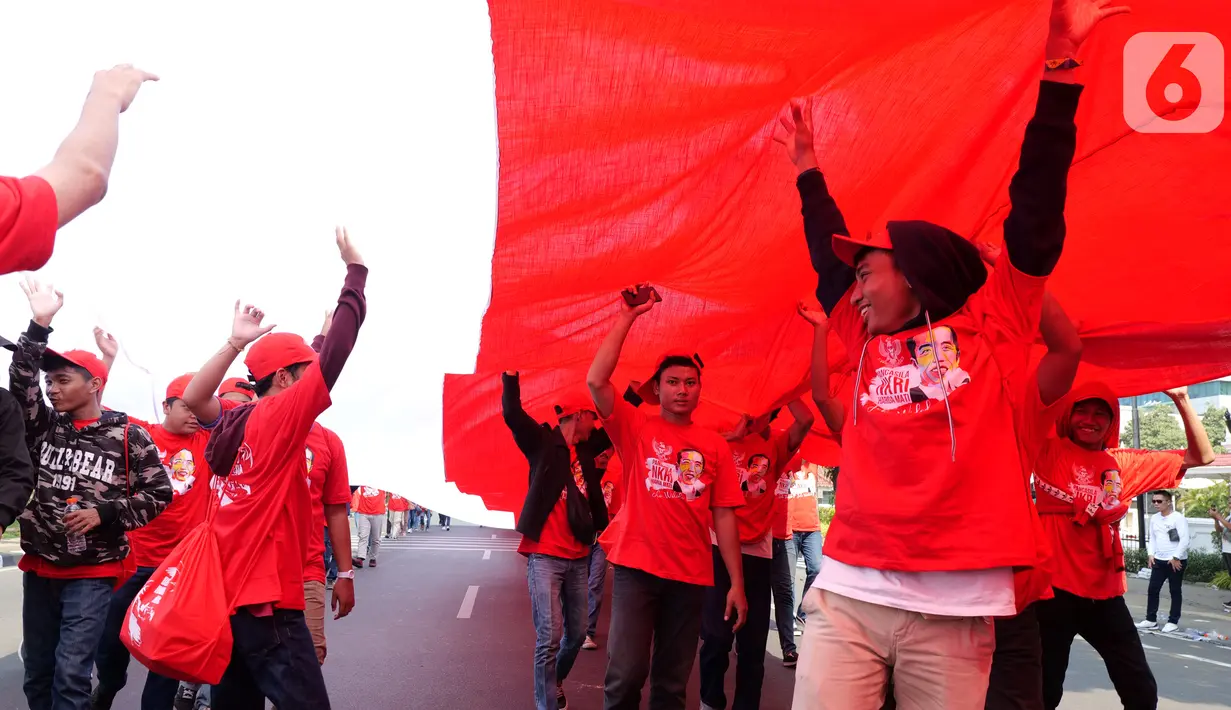 Sejumlah relawan membentangkan Bendera Merah Putih di kawasan jalan Medan Merdeka Selatan, Jakarta, Minggu (20/10/2019). Bendera Merah Putih Sekitar 200 meter dibentangkan jelang pelantikan Presiden-Wapres RI terpilih Joko Widodo-Ma'ruf Amin periode 2019-2024. (Liputan6.com/Herman Zakharia)