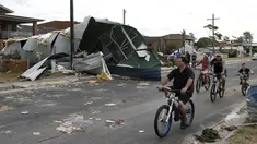 Warga bersepeda sambil mengamati kerusakan dari sebuah rumah akibat badai tornado yang langka di Kurnell pinggir Sydney, Rabu (16/12). Badai dengan hujan es disertai angin berkekuatan sampai 200 km per jam melanda kawasan tersebut. (REUTERS/Jason Reed)