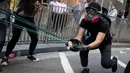 Demonstran menembakkan susu kemasan menggunakan sling shot ke arah polisi saat demonstrasi di Hong Kong, Senin (11/11/2019). Ketegangan di Hong Kong semakin meningkat setelah polisi menembak seorang demonstran hingga kritis. (AP Photo/Kin Cheung)