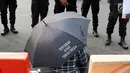 Seorang peserta aksi membawa payung hitam yang bertuliskan "Tuntaskan Kasus Tanjuang Priuk 84" saat menggelar aksi kamisan ke-493 di depan Istana Negara, Jakarta, Kamis (18/5). (Liputan6.com/Immanuel Antonius)