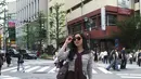 Saat berada di area persimpangan Tokyo, Febby tampil dengan nuansa preppy modern. Ia mengenakan striped top yang dipadukan midi skirt cokelat high waist. Sweater cokelat yang disampirkan di bahu memberi sentuhan old money aesthetic yang kini kembali tren. [@febbyrastanty].