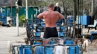 Seorang pria bersiap untuk berlatih mengangkat beban di outdoor gym atau pusat kebugaran terbuka di tepi Sungai Dnipro, Kiev, Ukraina, Kamis (18/4). Pusat kebugaran ini dibangun karena minimnya fasilitas olahraga yang terjangkau oleh warga. (AP Photo/Efrem Lukatsky)