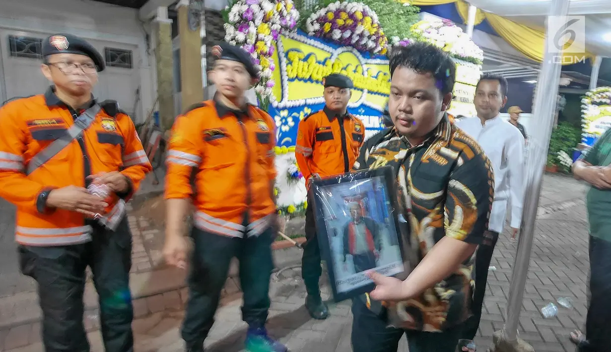 Putra almarhum Kapus Data Informasi dan Humas BNPB Sutopo Purwo Nugroho, Muhammad Ivanka Rizaldi Nugroho membawa pigura foto menuju Bandara Soekarno-Hatta usai disemayamkan di rumah duka Raffles Hils, Depok, Senin (7/7/2019). Sutopo akan dikebumikan di Boyolali. (Liputan6.com/Herman Zakharia)