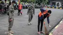 Petugas Satpol PP mengawasi warga yang menjalani sanksi sosial saat razia masker di kawasan Kota Tua, Jakarta, Kamis (24/2/2022). Pemerintah pusat kembali memperpanjang masa PPKM level 3 untuk wilayah Jakarta, Bogor, Depok, Tangerang dan Bekasi (Jabodetabek). (Liputan6.com/Faizal Fanani)