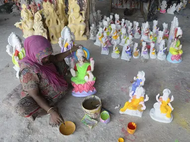 Seorang perajin mengecat patung dewi Hindu Lakshmi di sebuah lokakarya menjelang Diwali, festival lampu Hindu di pinggiran Hyderabad (28/10/2021). (AFP/Noah Seelam)