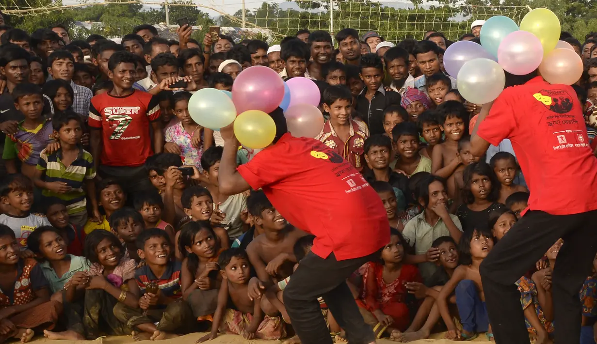 Kelompok teater Drama Therapy menghibur anak-anak pengungsian Rohingya di kamp pengungsi Kutupalong, Bangladesh (28/10). Para pemain teater ini menampilkan atraksi, sulap dan melawak badut untuk menghibur pengungsi Rohingya. (AFP Photo/Tauseef Mustafa)
