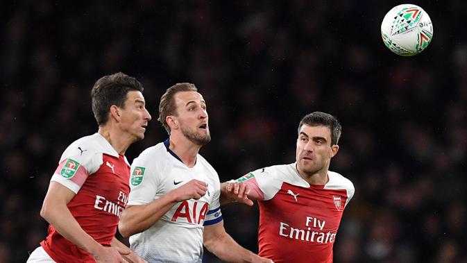 Bek Arsenal, Laurent Koscielny, berusaha merebut bola dari striker Tottenham, Harry Kane, pada laga perempat final Piala Liga di Stadion Emirates, London, Rabu (19/12). Arsenal kalah 0-2 dari Tottenham. (AFP/Ben Stansall)