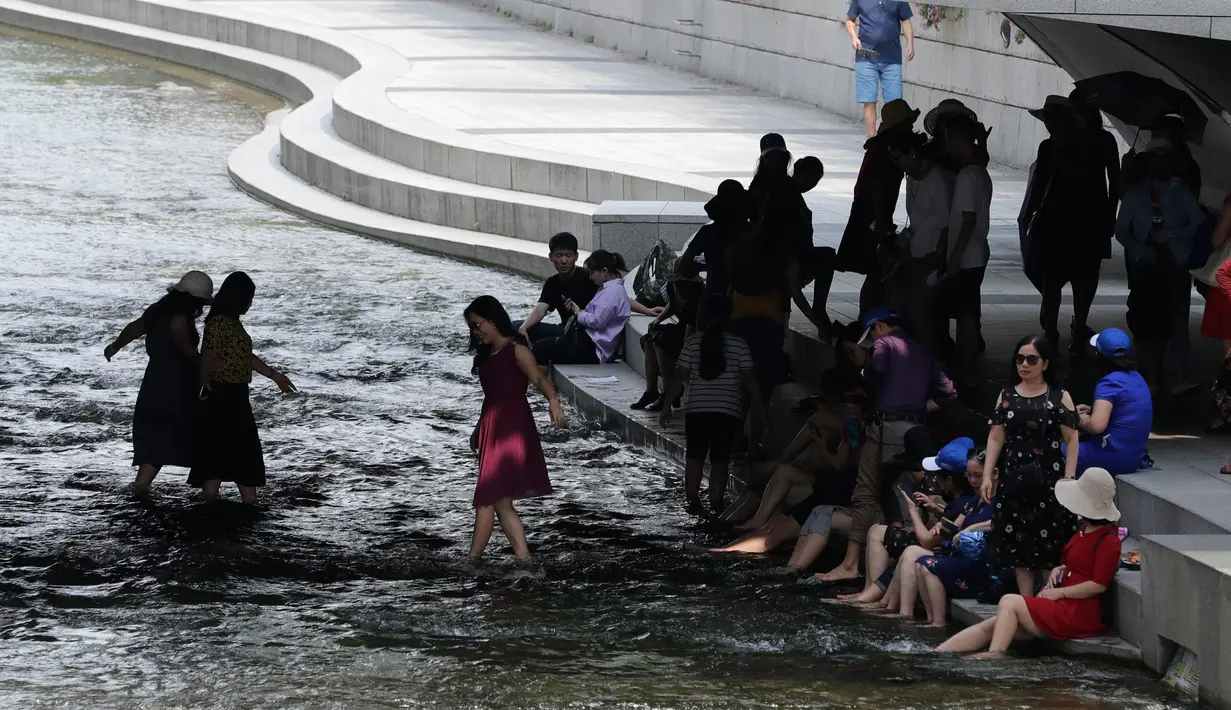 Warga bermain air saat siang hari di Sungai Cheonggye, Seoul, Korea Selatan, Senin (23/7). Korea Selatan tengah dilanda cuaca panas sepanjang pekan ini. (AP Photo/Lee Jin-man)