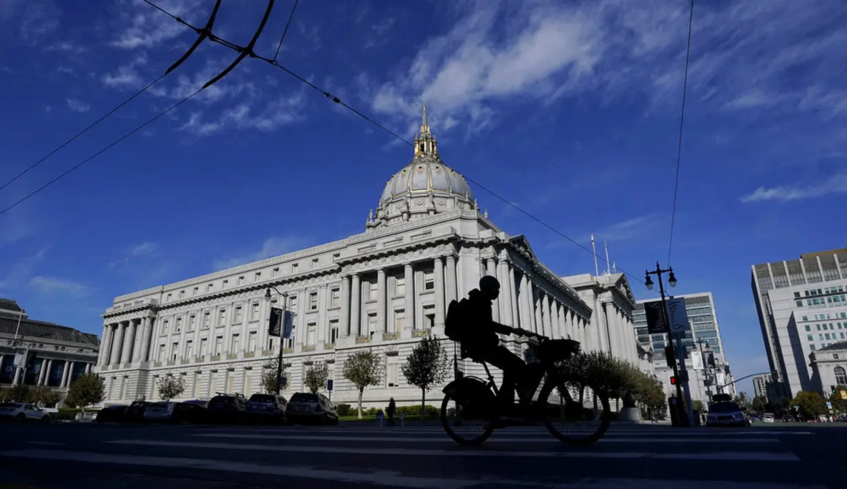 Pengendara sepeda berkendara melewati Balai Kota yang tetap buka hanya dengan perjanjian selama wabah COVID-19 di San Francisco, California, Amerika Serikat, Kamis (12/11/2020). California menjadi negara bagian kedua selain Texas yang mencatat 1 juta kasus infeksi COVID-19. (AP Photo/Jeff Chiu)