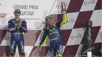 Pebalap Movistar Yamaha, Valentino Rossi (kanan), mengangkat trofi di podium setelah finis ketiga pada balapan MotoGP Qatar di Sirkuit Losail, Qatar, Minggu (26/3/2017). (Bola.com/Twitter/YamahaMotoGP)