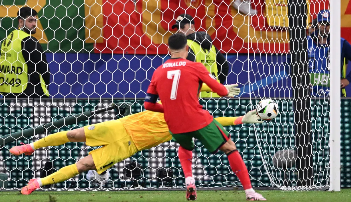 Kiper Slovenia Jan Oblak saat melakukan penyelamatan setelah tendangan penalti yang dilakukan oleh penyerang Portugal Cristiano Ronaldo selama pertandingan babak 16 besar Euro 2024 di Frankfurt Arena, pada 1 Juli 2024. (Kirill KUDRYAVTSEV/AFP)