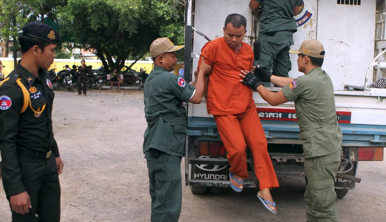 Yem Chrin (tengah) turun dari mobil kepolisian saat tiba di Pengadilan Provinsi Battambang,Kamboja,Kamis (3/12). Yem Chrin merupakan seorang tabib yang tinggal disuatu desa terpencil di Kamboja. (REUTERS/Stringer)