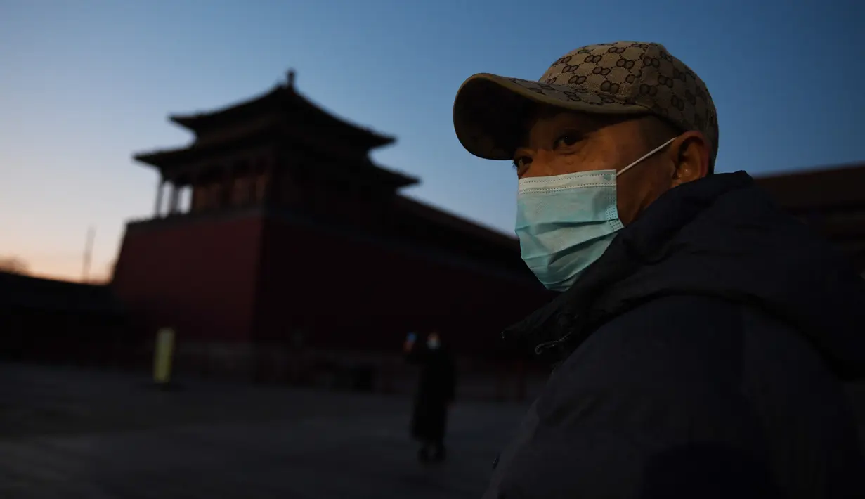 Seorang pria memakai masker pelindung di luar Kota Terlarang yang ditutup di Beijing pada Selasa (4/2/2020). Mencegah korban virus corona bertambah, China menutup  banyak destinasi wisata termasuk Kota Terlarang yang ditutup untuk kunjungan wisatawan sejak 24 Januari 2020 lalu. (GREG BAKER/AFP)