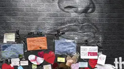 Orang-orang menempatkan pesan dukungan di mural Marcus Rashford yang dirusak di Withington, Manchester (12/7/2021). PM Inggris Boris Johnson mengutuk pelecehan rasis kepada tiga pemain Black England yang gagal mengeksekusi penalti melawan Italia di final Euro 2020. (Peter Byrne/PA via AP)