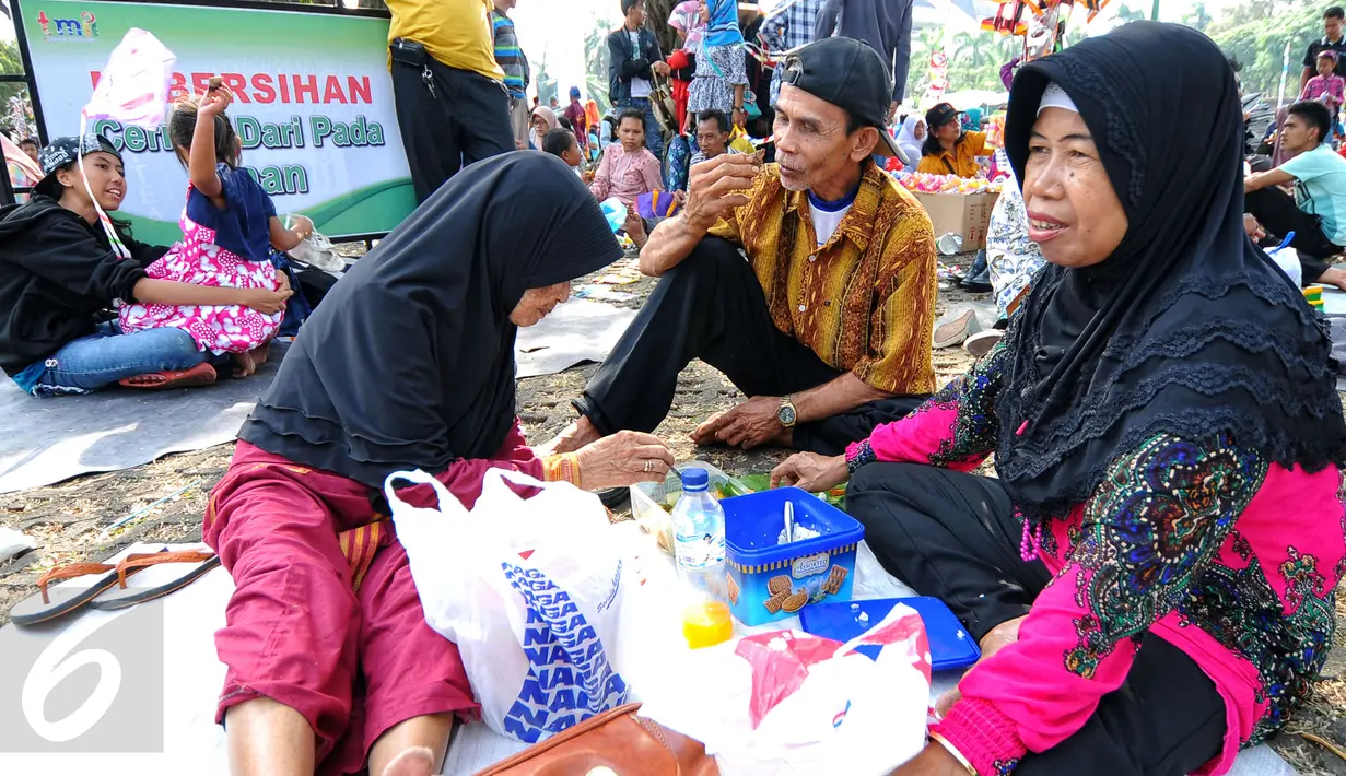 Tradisi makan bersama sambil menggelar tiker di tempat wisata menjadi pilihan sebagian besar warga yang mengunjungi tempat wisata Taman Mini Indonesia Indah, Jakarta, Minggu (19/07/2015). (Liputan6.com/Yoppy Renato)