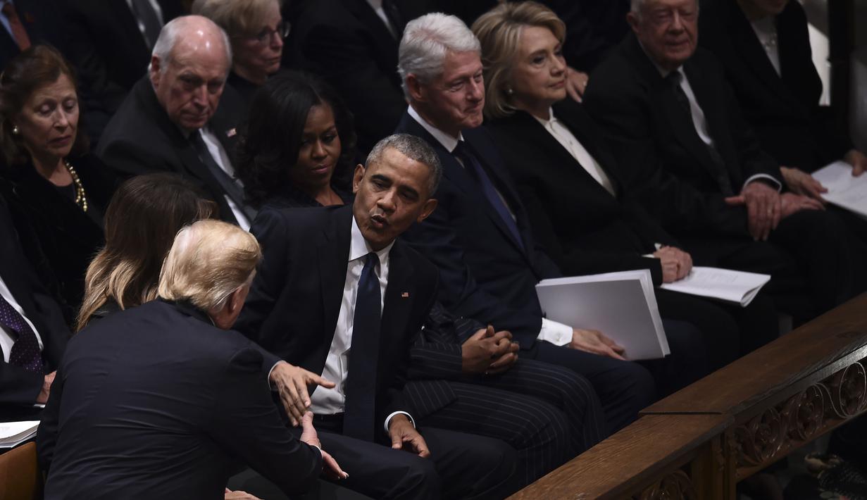 Presiden AS Donald Trump menyapa mantan presiden Barack Obama dan Michele Obama saat menghadiri prosesi pemakaman kenegaraan Presiden AS ke-41, George HW Bush di Katedral Nasional Washington, Rabu (5/12). (Brendan SMIALOWSKI/AFP)