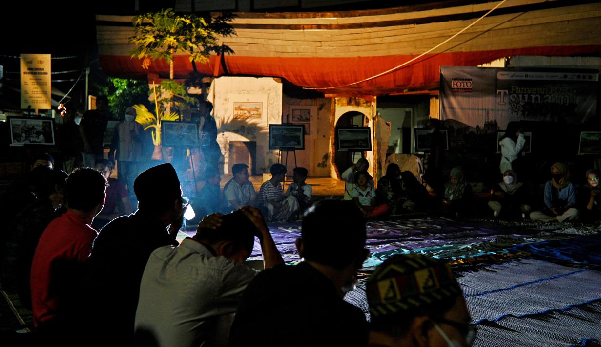 Sejumlah warga menghadiri doa bersama pada malam peringatan 17 tahun tsunami Boxing Day 2004 di monumen Kapal Tsunami Lampulo di Banda Aceh (25/12/2021). (AFP/Chaideer Mahyuddin)