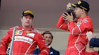 Pebalap Ferrari, Kimi Raikkonen (kiri), memandang Sebastian Vettel yang merayakan kemenangan di  F1 GP Monako, Minggu (28/5/2017). (AP Photo/Claude Paris)