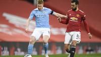 Gelandang Manchester City Kevin De Bruyne (kiri) bersaing dengan gelandang Manchester United Bruno Fernandes pada leg pertama semifinal Piala Liga Inggris di Old Trafford pada 6 Januari 2021. (PETER POWELL / KOLAM RENANG / AFP)